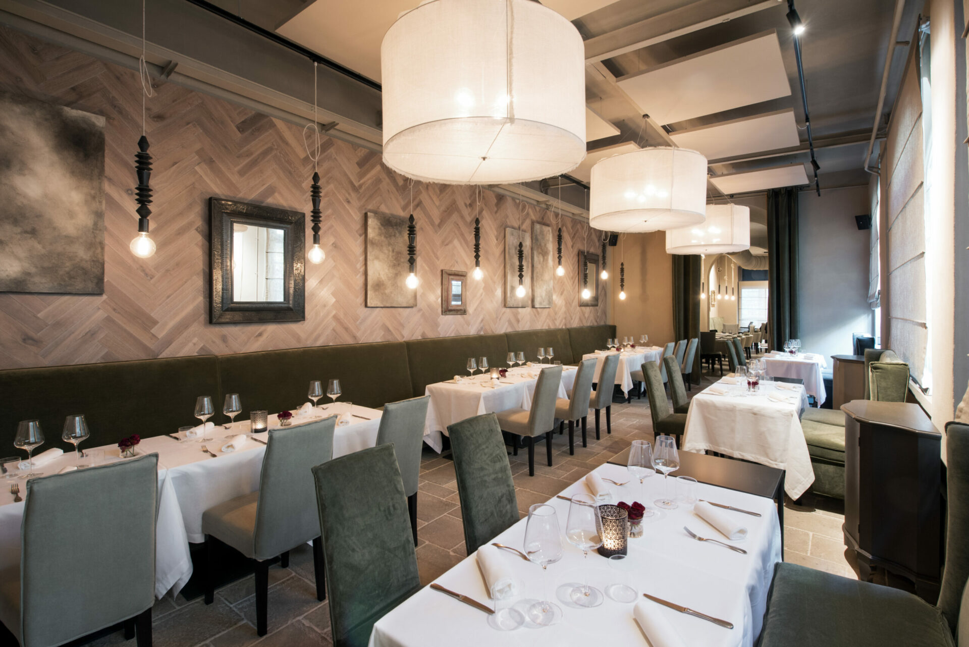 Interior of a modern upmarket restaurant with empty tables set with cloths, cutlery and glassware in a receding view