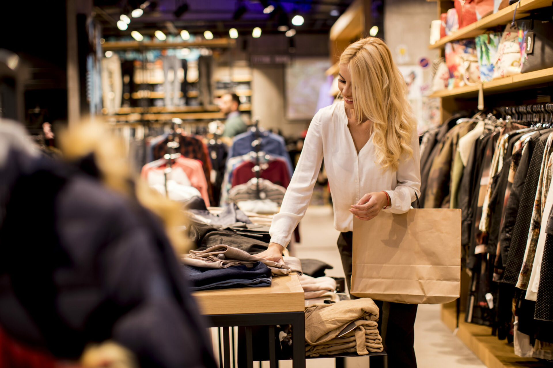 Beautiful young woman with shopping bags standing at the clothing store